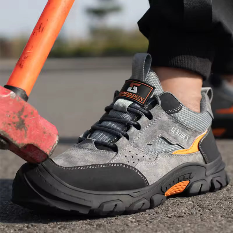 Gray work boot with orange accents worn by a person holding a red tool.